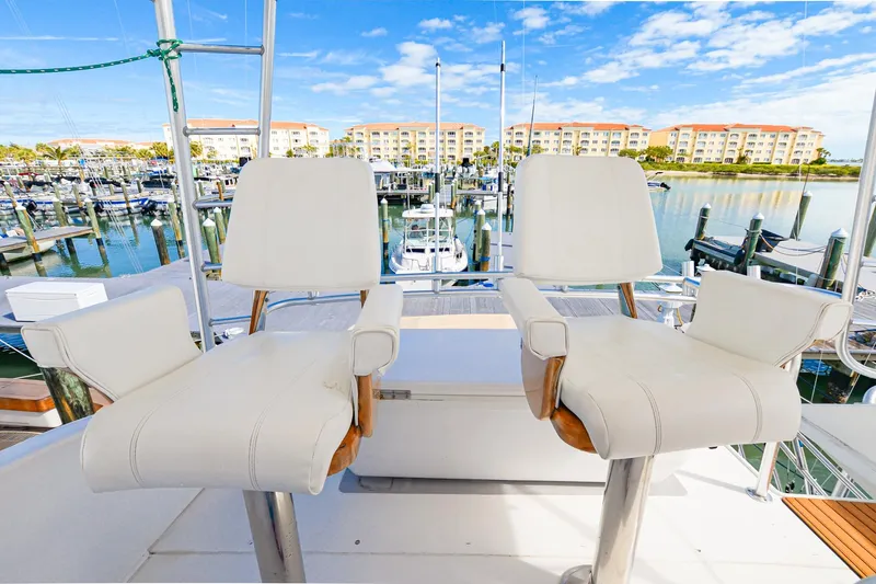 Slide: The Image of Two white captain's chairs on a 1999 Viking 55 Convertible yacht, overlooking a marina. - 23