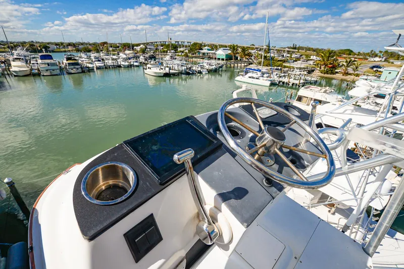 Slide: The Image of Helm of 1999 Viking 55 Convertible yacht overlooking marina with boats and clear sky. - 26