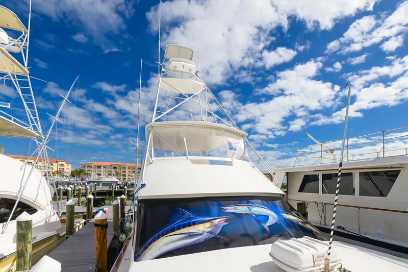 Slide: The Image of 1999 Viking 55 Convertible yacht docked under a vibrant blue sky. - 30