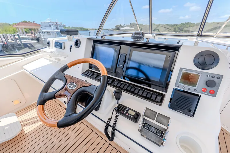 Slide: The Image of 2005 Sea Ray 550 Sedan Bridge helm with modern navigation equipment and wooden steering wheel. - 35