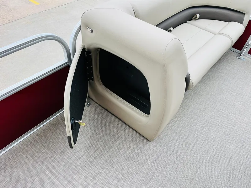 Slide: The Image of 2025 Sun Tracker Party Barge 18 DLX with open storage compartment on beige seating. - 14