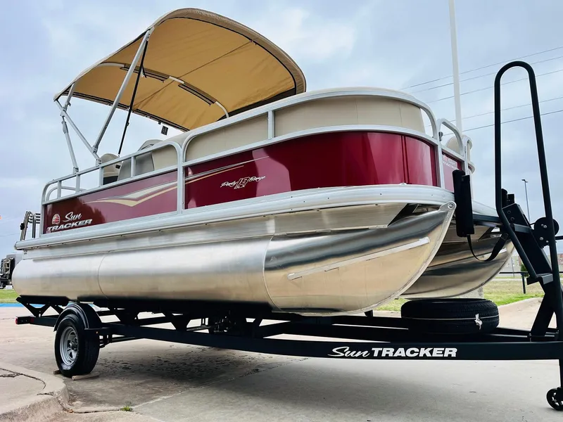 Slide: The Image of 2025 Sun Tracker Party Barge 18 DLX pontoon boat on trailer, red and silver design. - 5