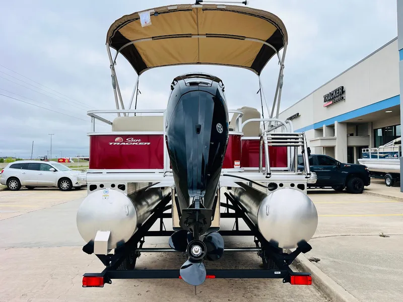 Slide: The Image of 2025 Sun Tracker Party Barge 18 DLX pontoon boat with outboard motor, parked outdoors. - 8