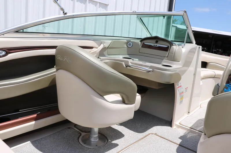 Slide: The Image of Interior of a 2004 Sea Ray 220 Select boat, featuring beige seating and dashboard. - 26