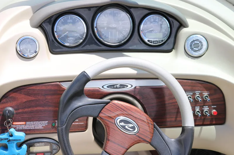 Slide: The Image of Steering wheel and dashboard of 2004 Sea Ray 220 Select boat, featuring wood accents and gauges. - 36