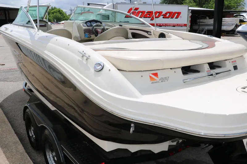 Slide: The Image of 2004 Sea Ray 220 Select boat on trailer, white and black exterior, parked outdoors. - 7