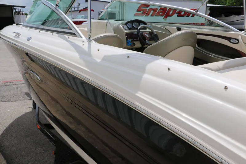 Slide: The Image of 2004 Sea Ray 220 Select boat with beige interior, parked near Snap-on sign. - 8