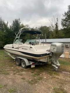Slide: The Image of 2002 Hurricane 217 Sundeck boat on trailer with Honda outboard motor, parked outdoors. - 1