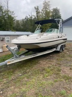 Slide: The Image of 2002 Hurricane 217 Sundeck boat on trailer, parked outdoors near a building. - 2