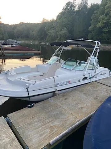 Slide: The Image of 2002 Hurricane 217 Sundeck boat docked on a calm lake with surrounding trees. - 7