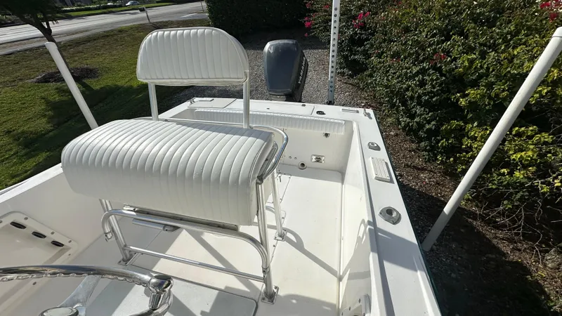Slide: The Image of 1998 Mako 232 Center Console boat with white seating and outboard motor, parked outdoors. - 6