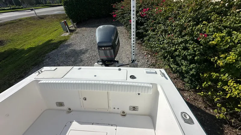 Slide: The Image of 1998 Mako 232 Center Console boat with outboard motor, parked near greenery. - 8