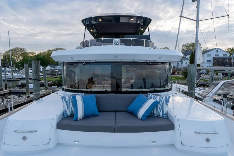 Slide: The Image of 2024 Sirena 58 Flybridge yacht with cushioned seating and blue pillows at a marina. - 15