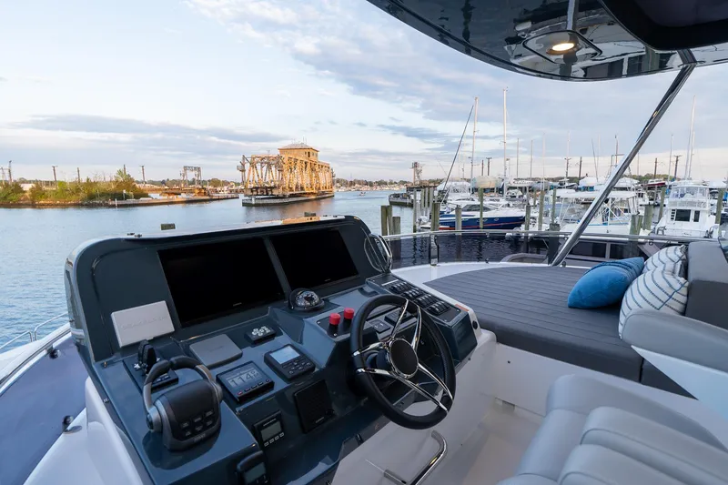 Slide: The Image of 2024 Sirena 58 Flybridge yacht cockpit with marina view and modern controls. - 32