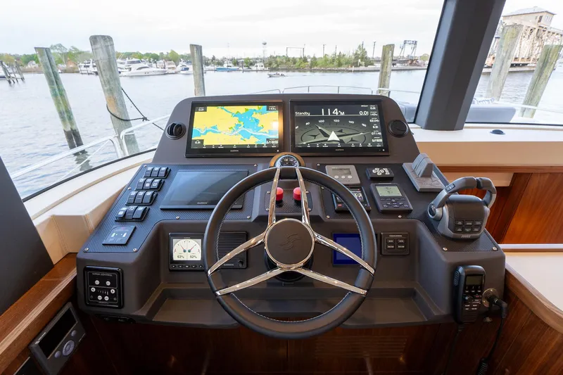 Slide: The Image of 2024 Sirena 58 Flybridge helm with advanced navigation displays and controls, docked at marina. - 46