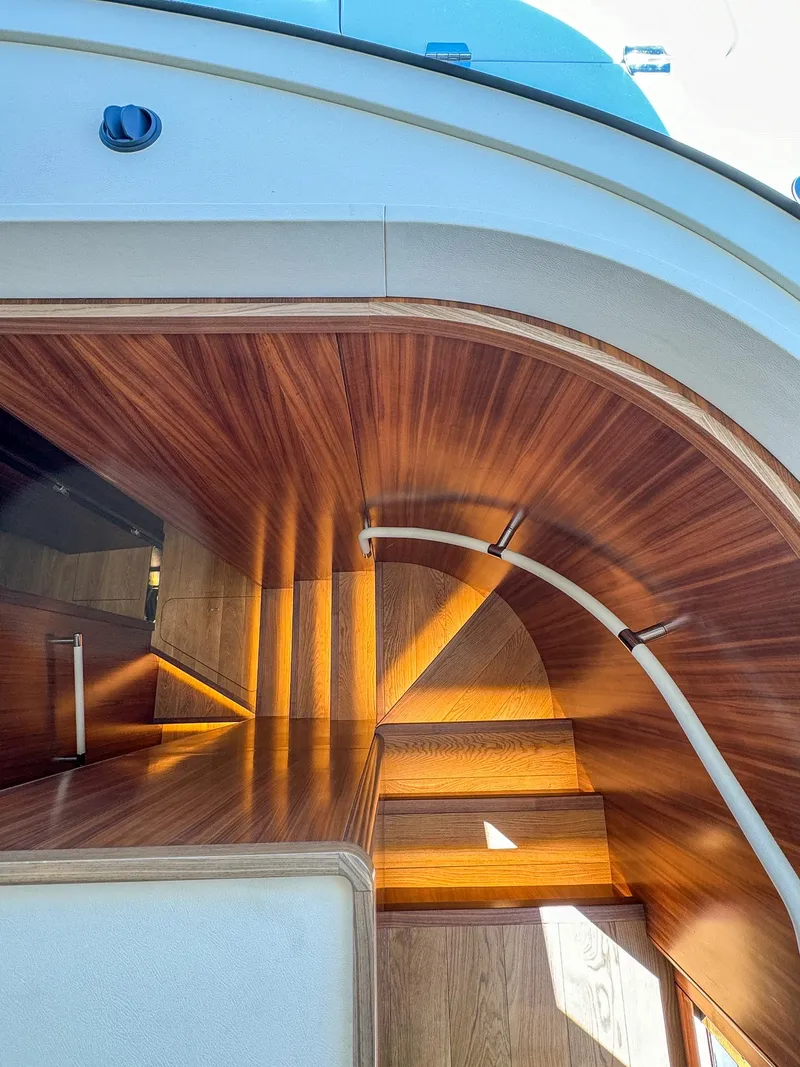 Slide: The Image of Curved wooden staircase on 2024 Sirena 58 Flybridge yacht, showcasing elegant design. - 47