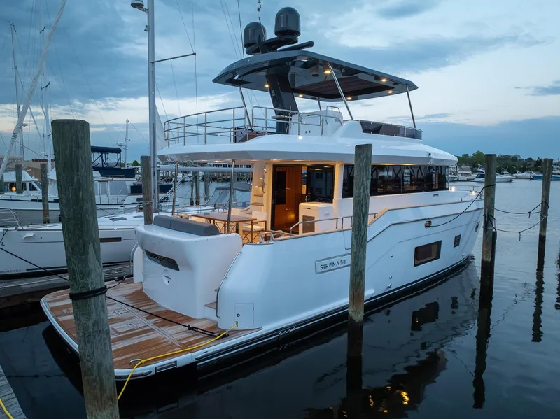 Slide: The Image of 2024 Sirena 58 Flybridge yacht docked at marina during twilight. - 7