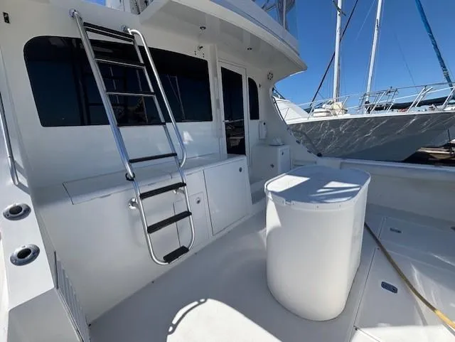 Slide: The Image of 2007 Jersey Cape 44 CNV yacht deck with ladder and storage, under clear blue sky. - 14