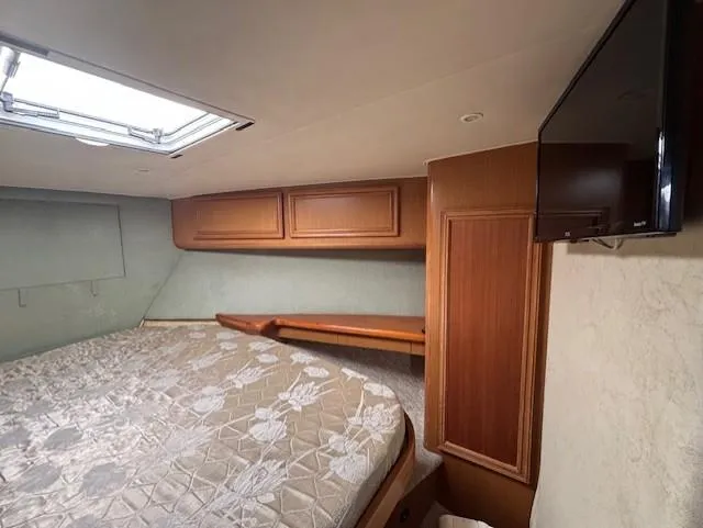 Slide: The Image of Interior of 2007 Jersey Cape 44 CNV boat with bed, wooden cabinets, and TV. - 47