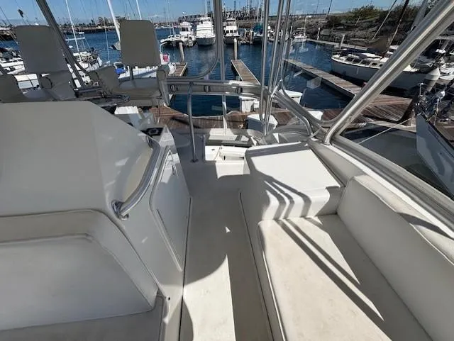 Slide: The Image of 2007 Jersey Cape 44 CNV yacht interior with marina view, featuring white seating and helm station. - 5