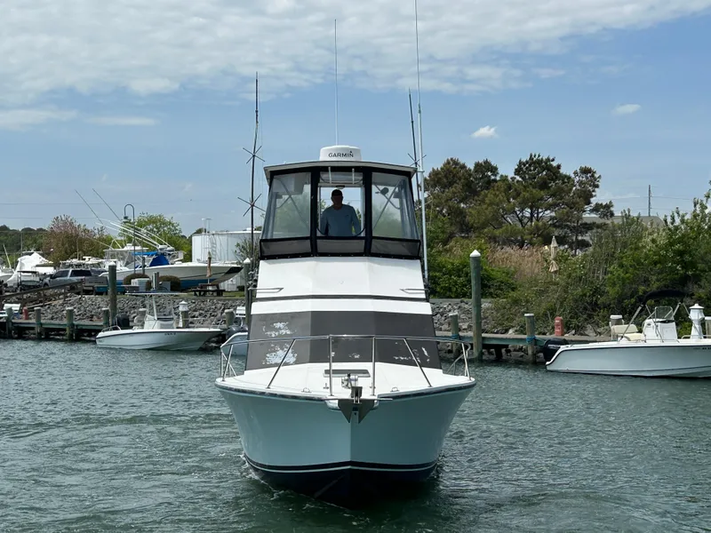Slide: The Image of 1990 Albemarle 325 Convertible boat navigating a marina with clear skies. - 2