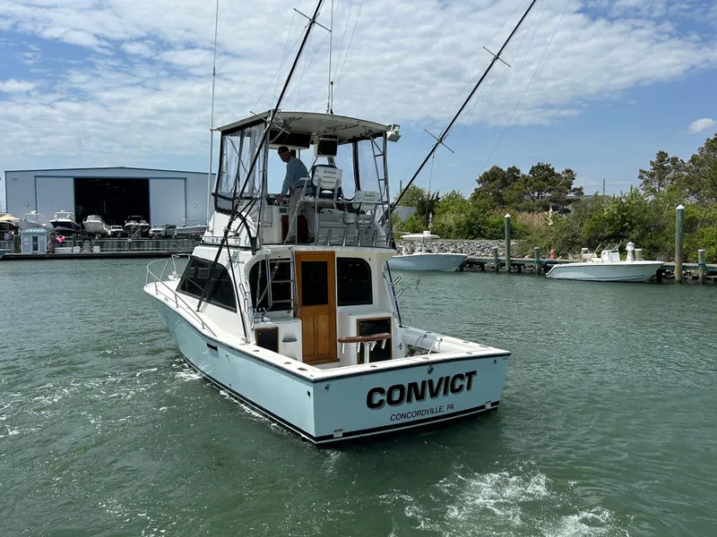Slide: The Image of 1990 Albemarle 325 Convertible boat on water, rear view, with fishing rods and marina background. - 3