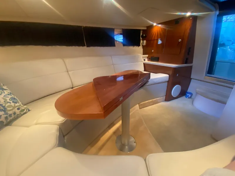 Slide: The Image of Interior of 2005 Regal 3350 Sport Cruiser with white seating and wooden table. - 45