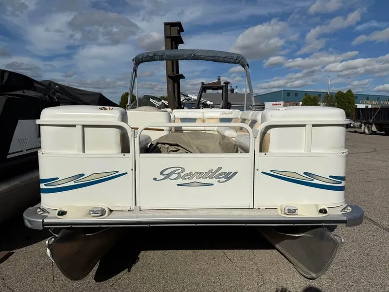 Slide: The Image of 2008 Bentley Pontoons 180 CRUISE boat, white with blue accents, parked outdoors under a cloudy sky. - 1