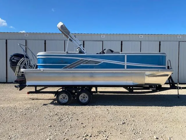 The Image of 2025 SunCatcher Fusion 322RC pontoon boat on trailer, blue and silver design. - 0