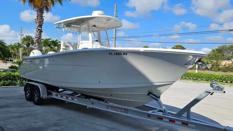Slide: The Image of 2019 Cobia 280 Center Console boat on trailer, parked outdoors under blue sky. - 0