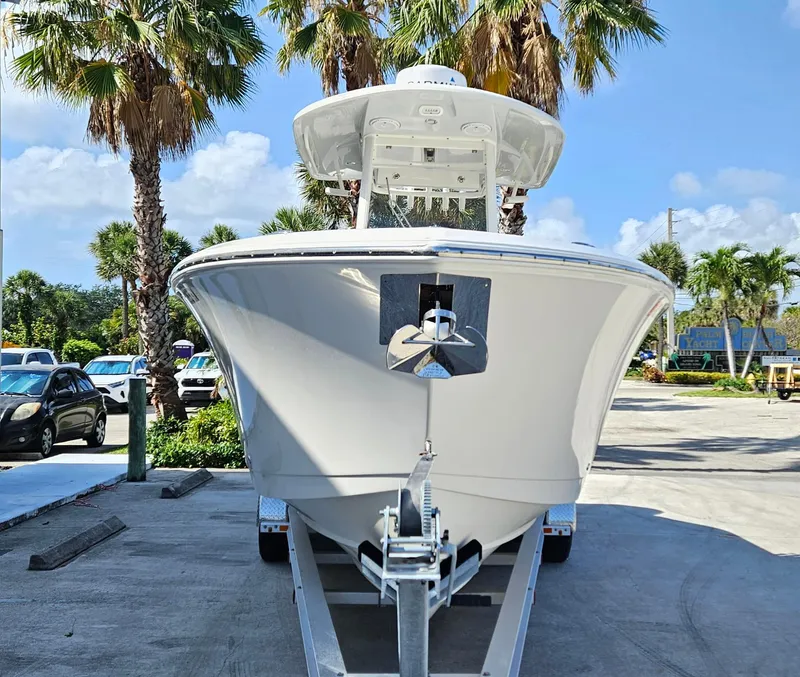 Slide: The Image of 2019 Cobia 280 Center Console boat on trailer, surrounded by palm trees. - 2
