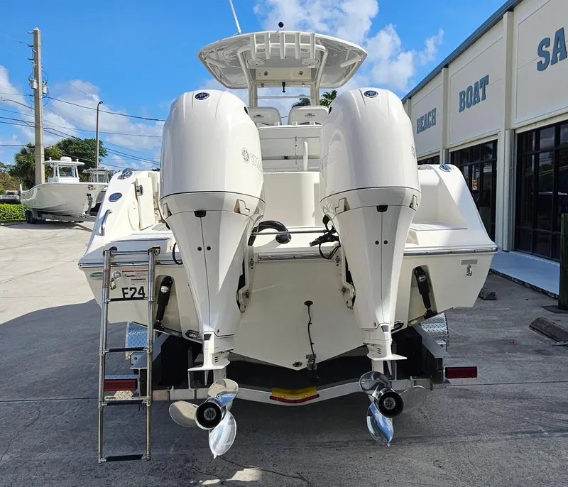 Slide: The Image of 2019 Cobia 280 Center Console boat with dual outboard engines, parked outside a marine shop. - 4