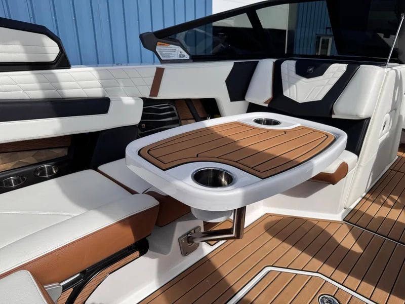 Slide: The Image of 2022 Nautique Super Air Nautique G21 interior with stylish seating and table, featuring cup holders. - 15