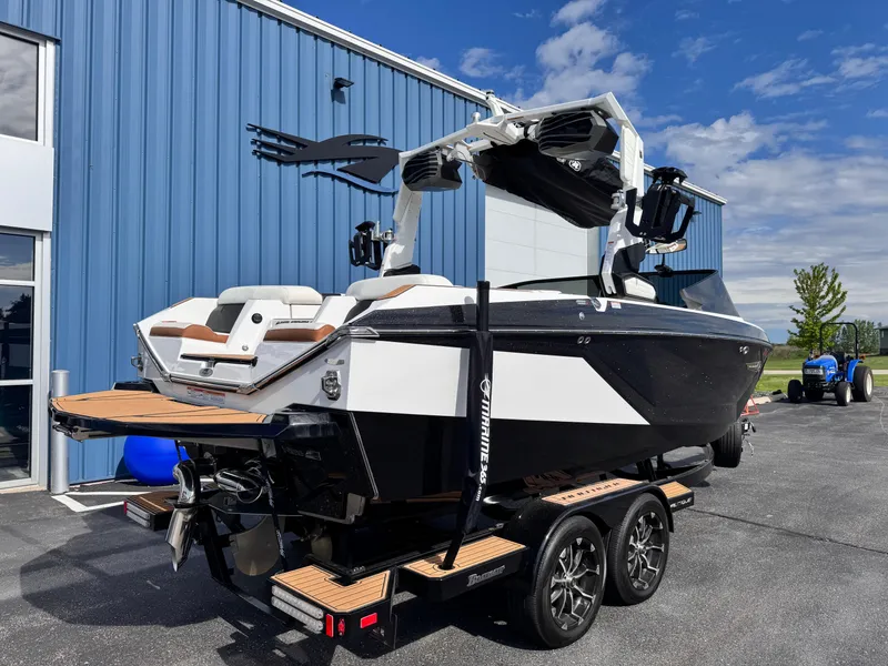 Slide: The Image of 2022 Nautique Super Air Nautique G21 boat on trailer, parked near blue building. - 3