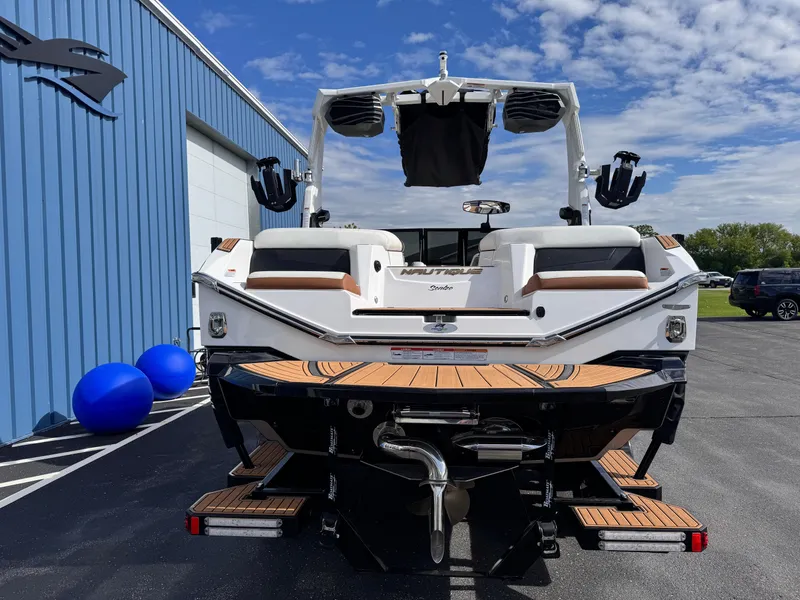 Slide: The Image of 2022 Nautique Super Air Nautique G21 boat, rear view, parked near blue building. - 4