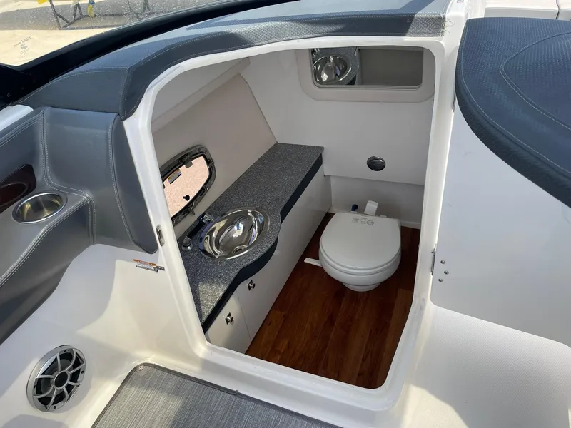 Slide: The Image of 2017 Chaparral 307 SSX boat interior with compact bathroom and wooden flooring. - 16