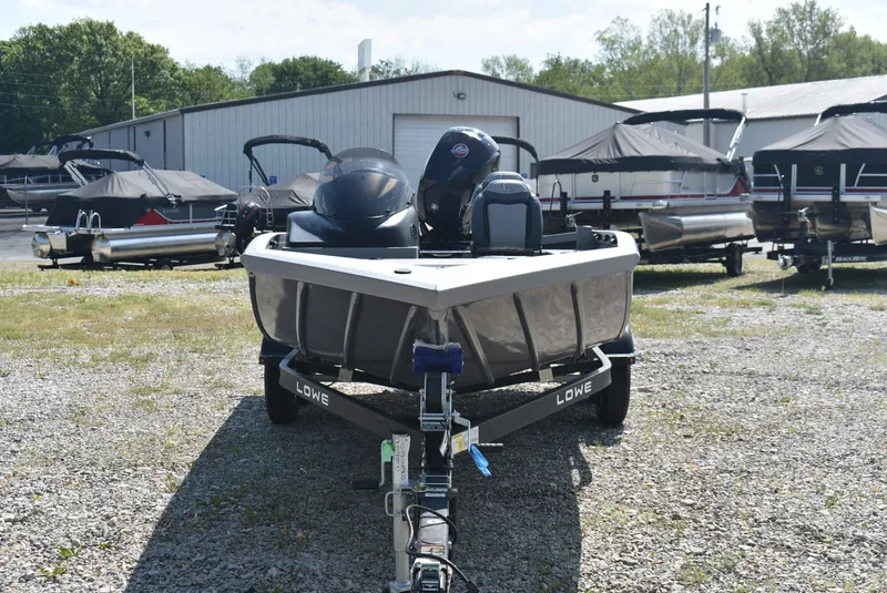 Slide: The Image of Front view of a 2025 Lowe Outlet 20 boat on a trailer in a marina. - 2