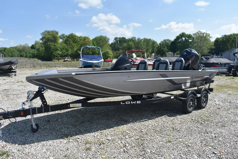 Slide: The Image of 2025 Lowe Outlet 20 boat on trailer, parked outdoors on gravel. - 3