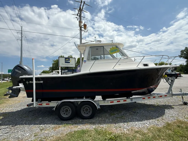 The Image of 2024 NorthCoast 235 HT boat on trailer, parked outdoors under a partly cloudy sky. - 1