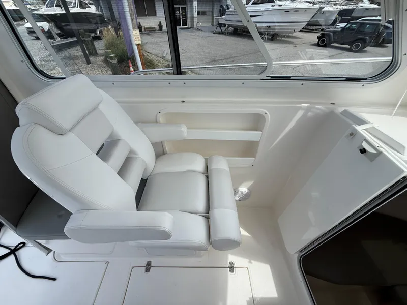 Slide: The Image of 2024 NorthCoast 235 HT boat interior with white cushioned seating and window view. - 13