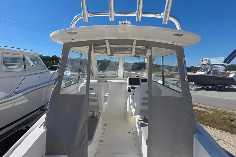 Slide: The Image of 2024 NorthCoast 235 HT boat interior with helm and seating, displayed outdoors. - 18