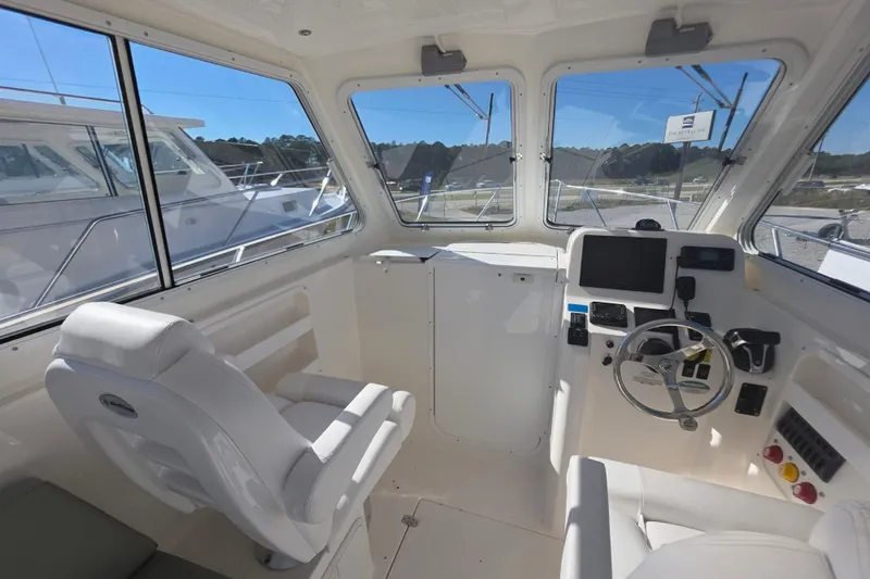Slide: The Image of 2024 NorthCoast 235 HT boat interior with helm, steering wheel, and seating. - 20