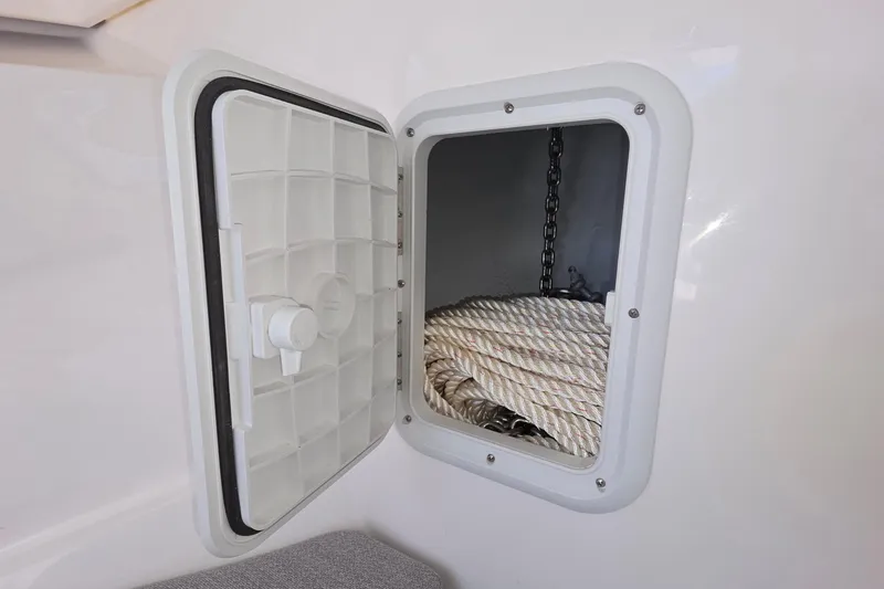 Slide: The Image of Open storage compartment on 2024 NorthCoast 235 HT boat, containing coiled rope and chain. - 32
