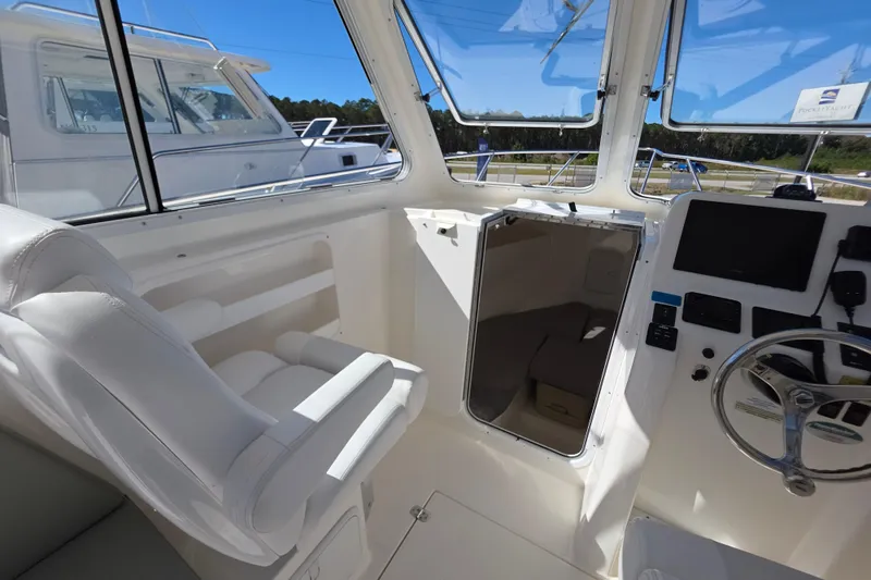 Slide: The Image of 2024 NorthCoast 235 HT boat interior with helm, seating, and cabin entrance. - 33