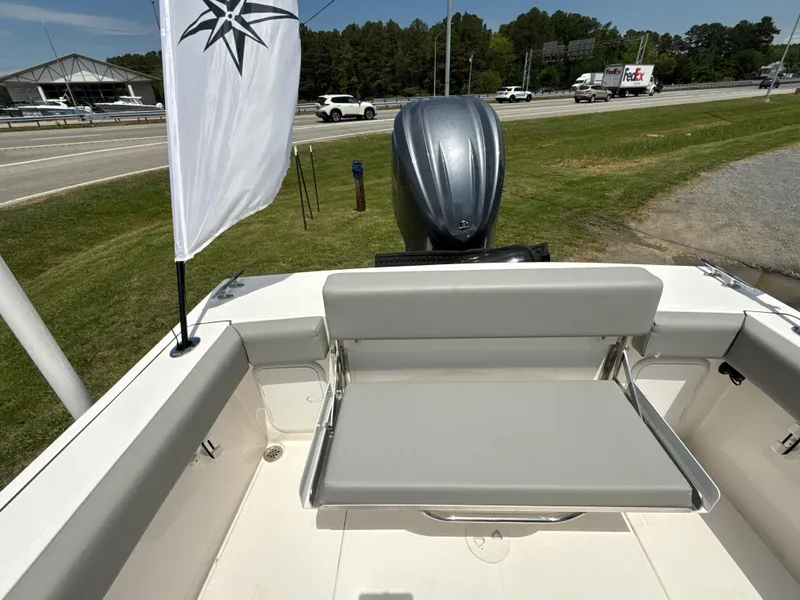 Slide: The Image of 2024 NorthCoast 235 HT boat with seating and outboard motor, parked near a road. - 4