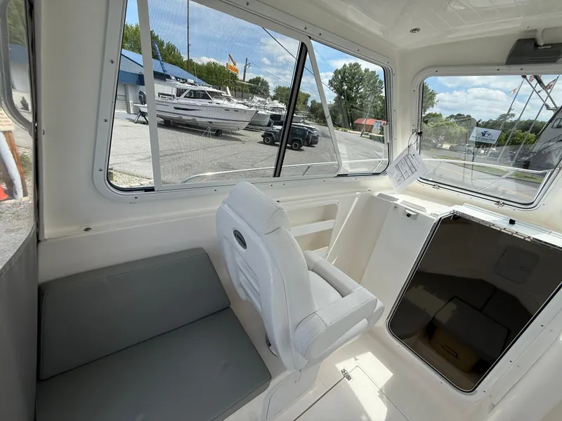 Slide: The Image of 2024 NorthCoast 235 HT boat interior with seating and windows, docked at a marina. - 9