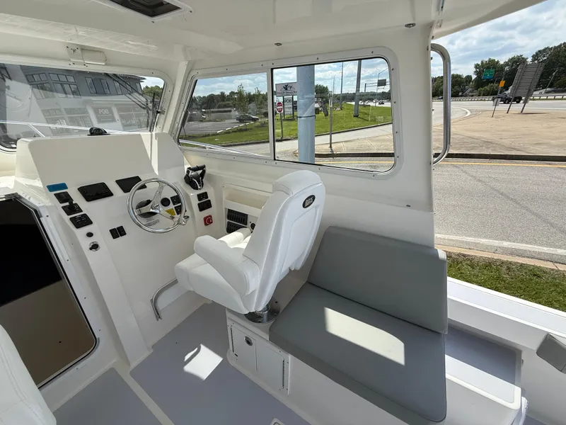 Slide: The Image of 2025 NorthCoast 255 HT boat deck with twin engines, flags, and road view. - 5