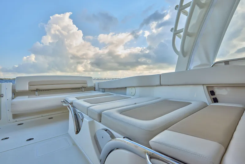 Slide: The Image of 2016 Boston Whaler 320 Vantage boat interior with cushioned seating and cloudy sky backdrop. - 15