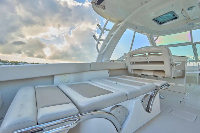 Slide: The Image of 2016 Boston Whaler 320 Vantage interior with cushioned seating under a cloudy sky. - 16