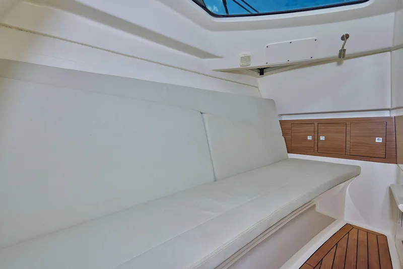 Slide: The Image of Interior of 2016 Boston Whaler 320 Vantage boat with cushioned seating and wooden accents. - 24